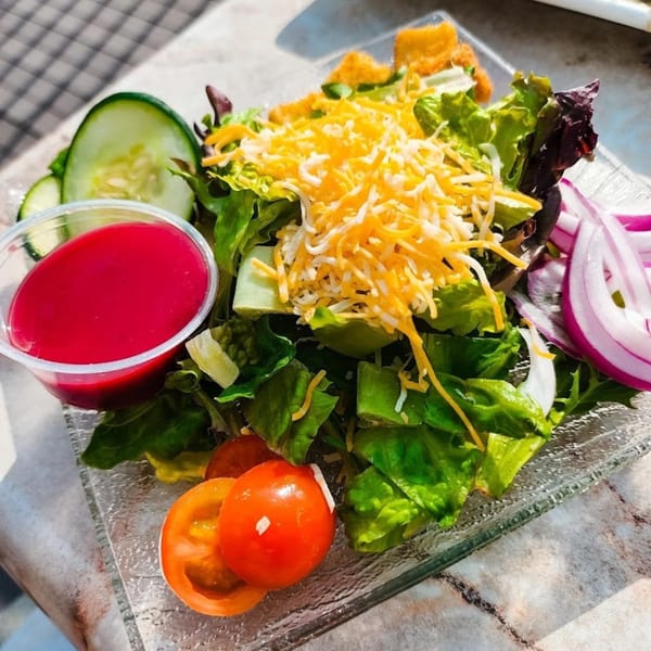 Dunmire's on the Lakes house salad with mixed greens, cheese, cucumbers, tomatoes, red onion, and dressing.